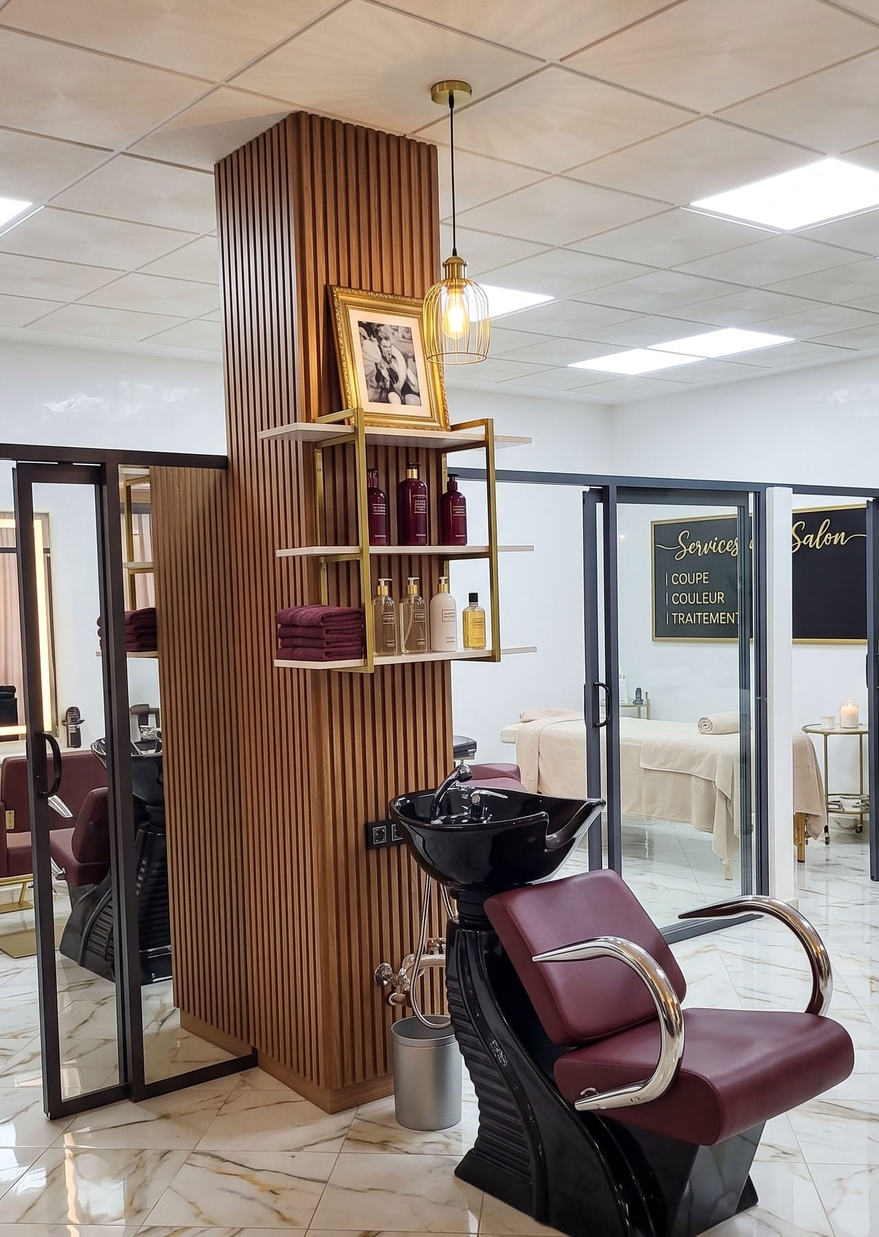Coin salon de New Style — marbre Calacatta et fauteuil bordeaux, lumière de fin de journée.