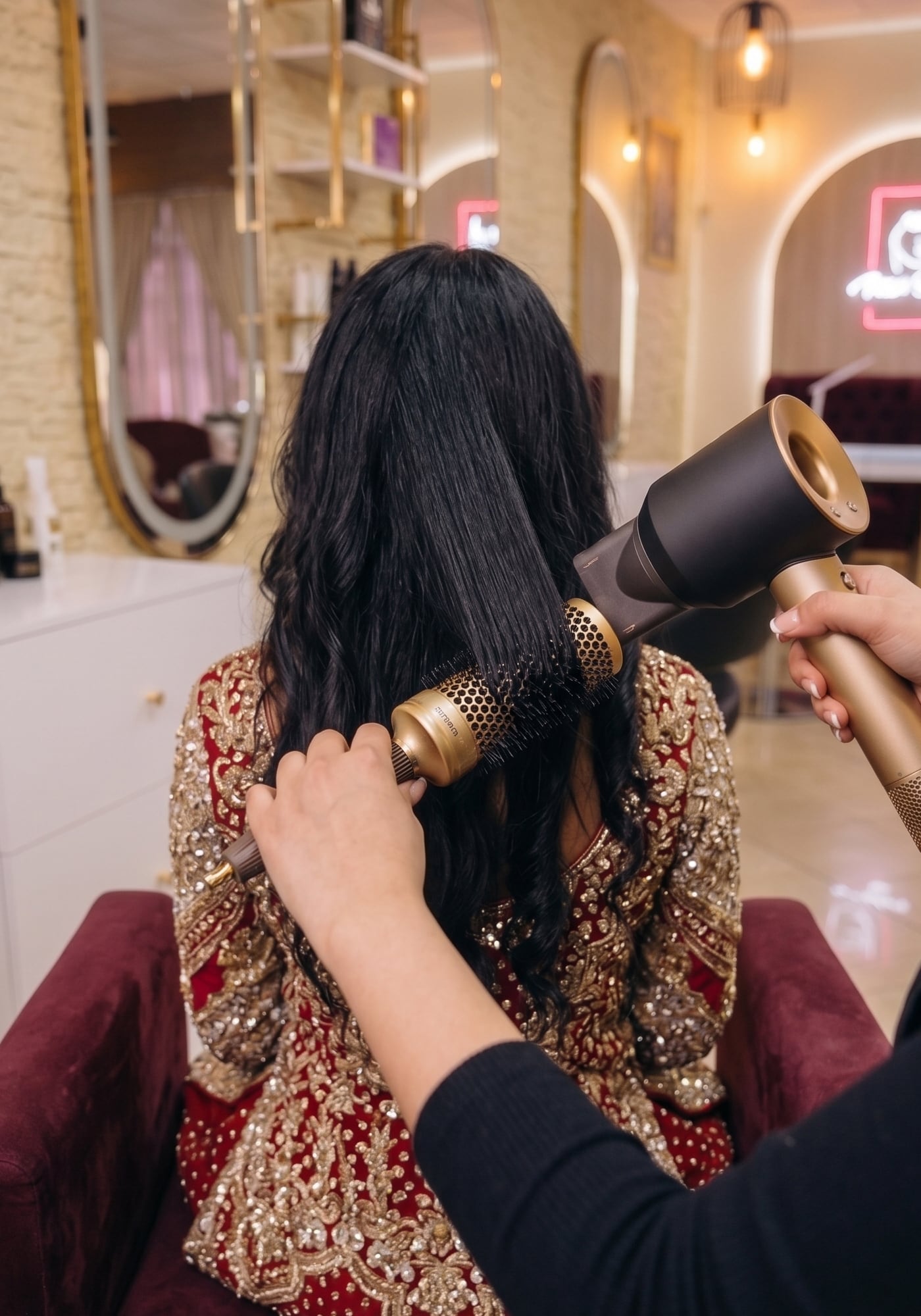 Préparation coiffure mariée — robe brodée or, chignon travaillé à la main.